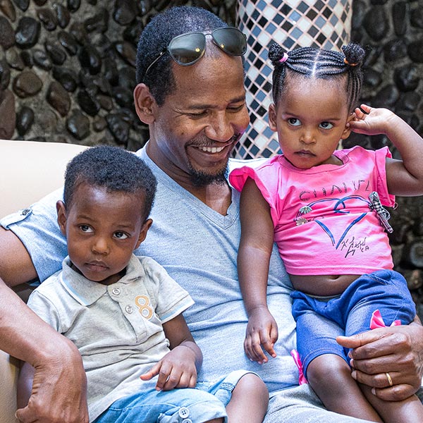 ethiopian father sitting with two children on his lap