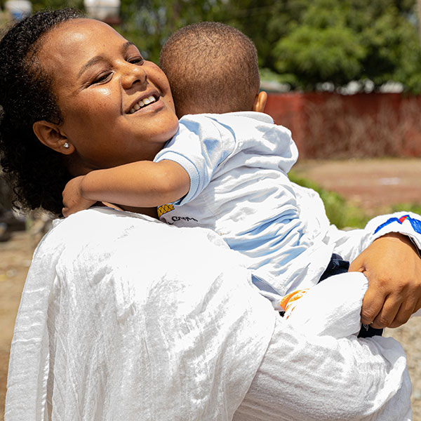 Ethiopian mother hugs young toddler in her arms.